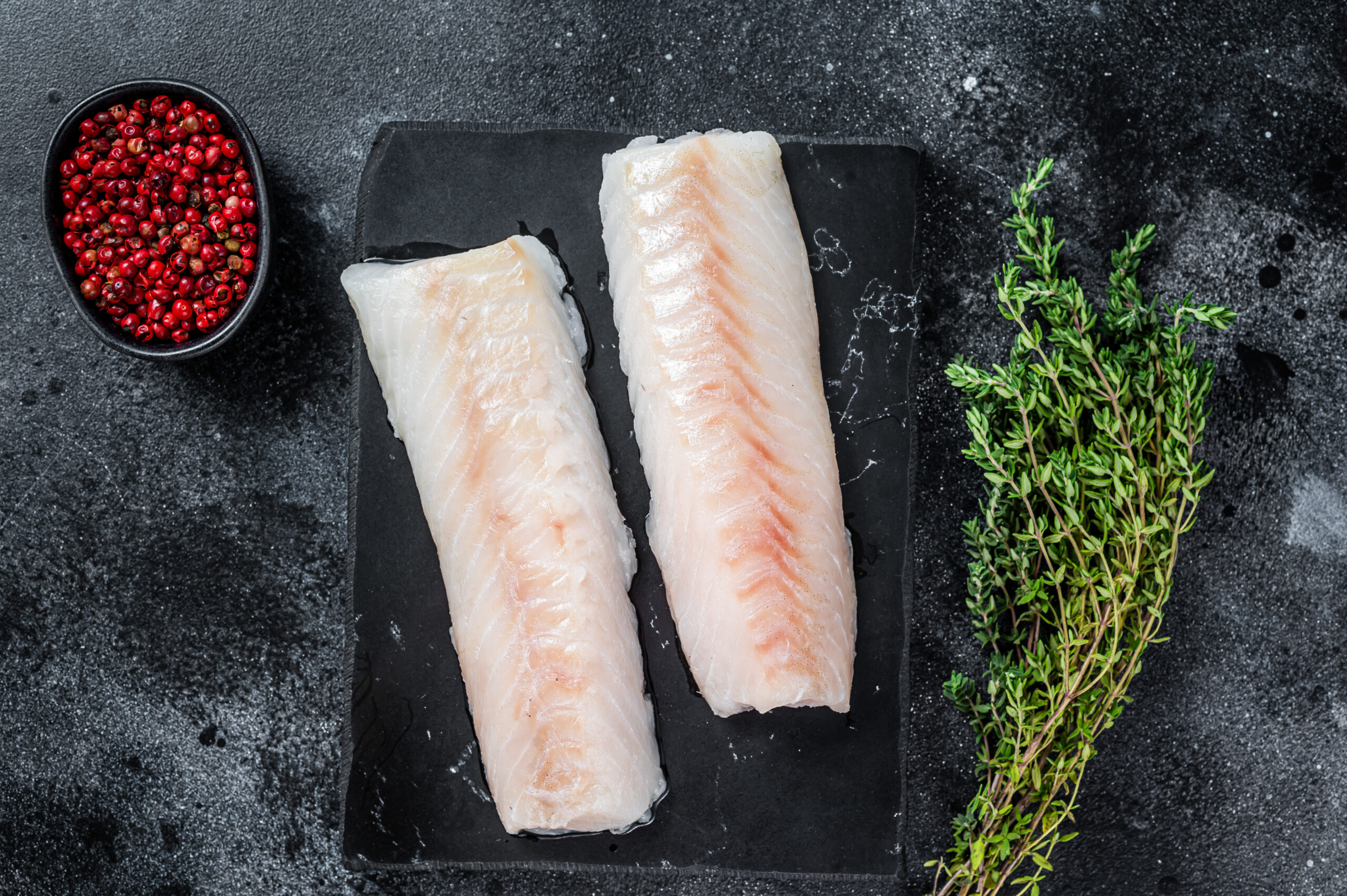 Raw,Cod,Loin,Fillet,Fish,On,Marble,Board.,Black,Background.